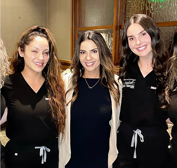 Three women smiling together at an event.
