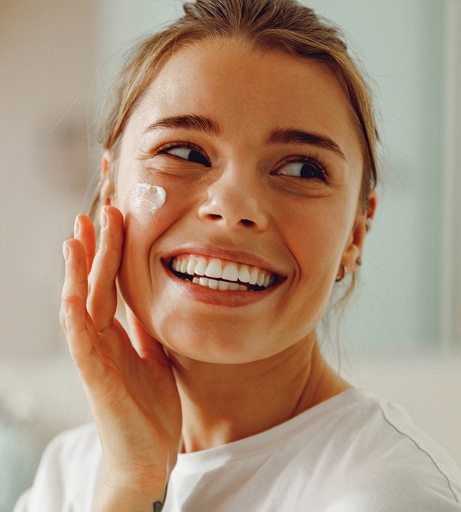 Woman applying skincare with a smile.