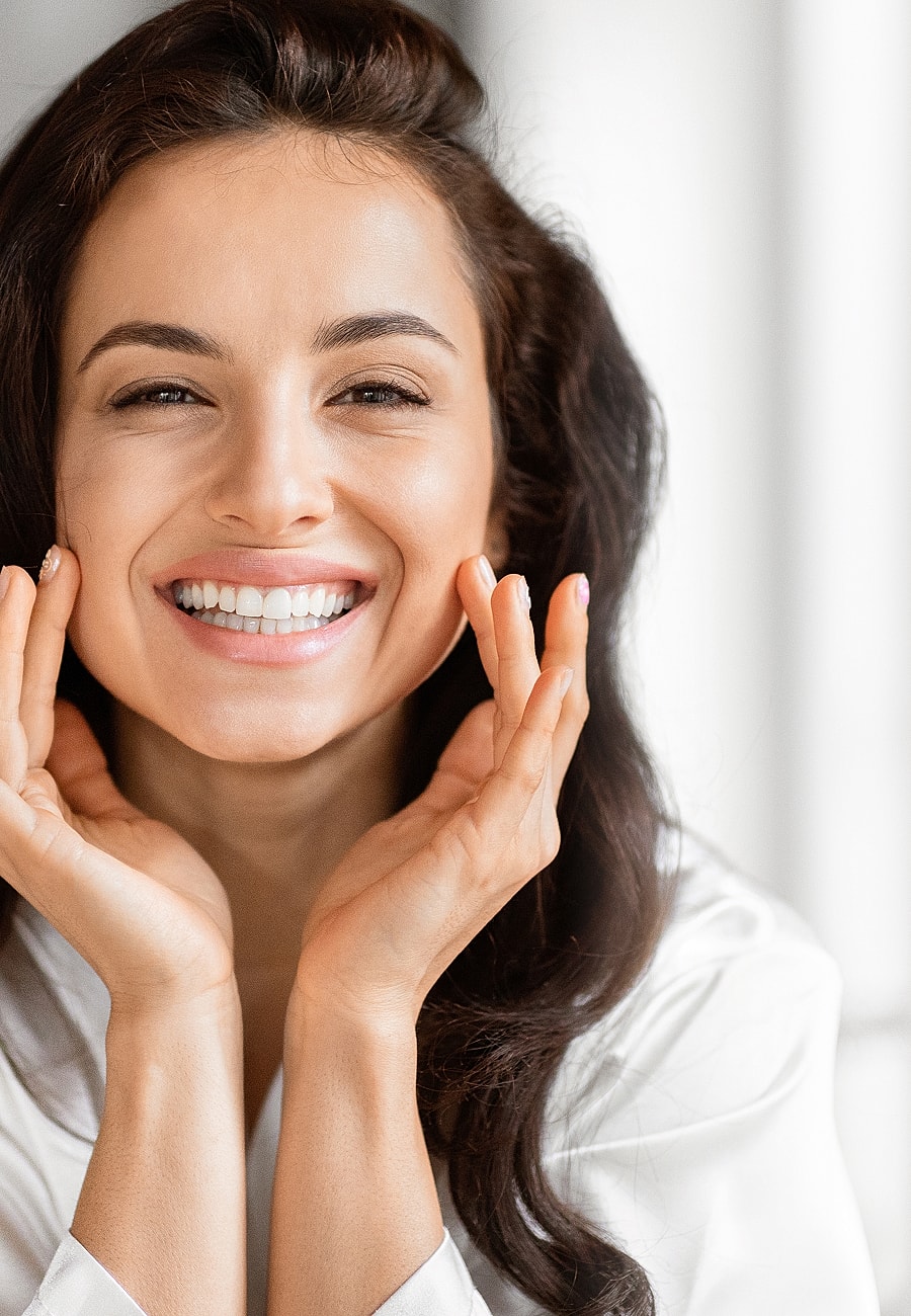Smiling woman with hands on face.