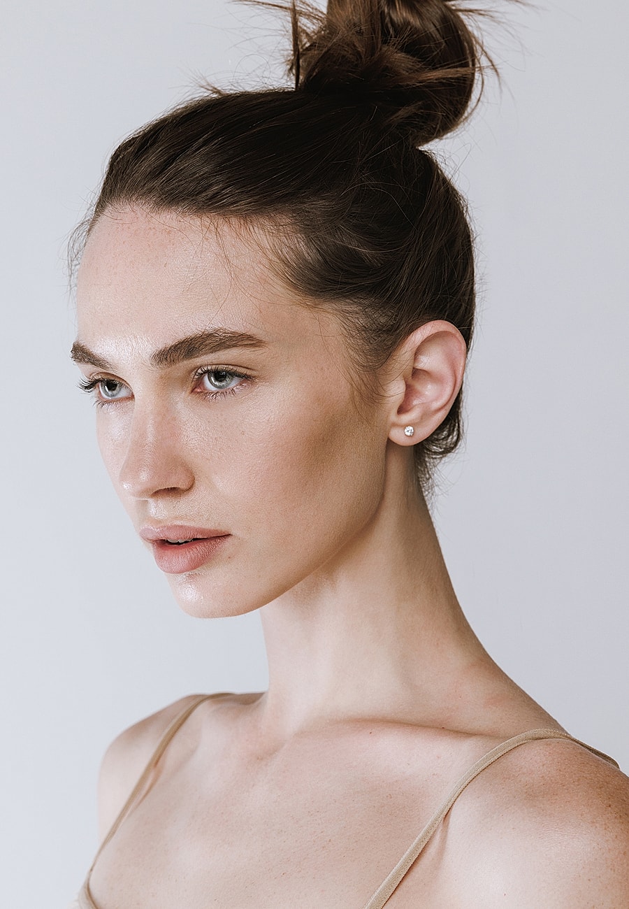 Female model with a sleek bun hairstyle.