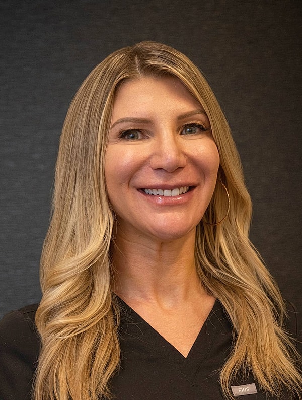 Smiling woman with long hair in scrubs.