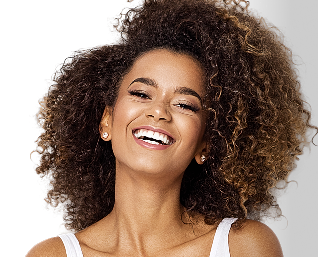 Smiling woman with curly hair against black background
