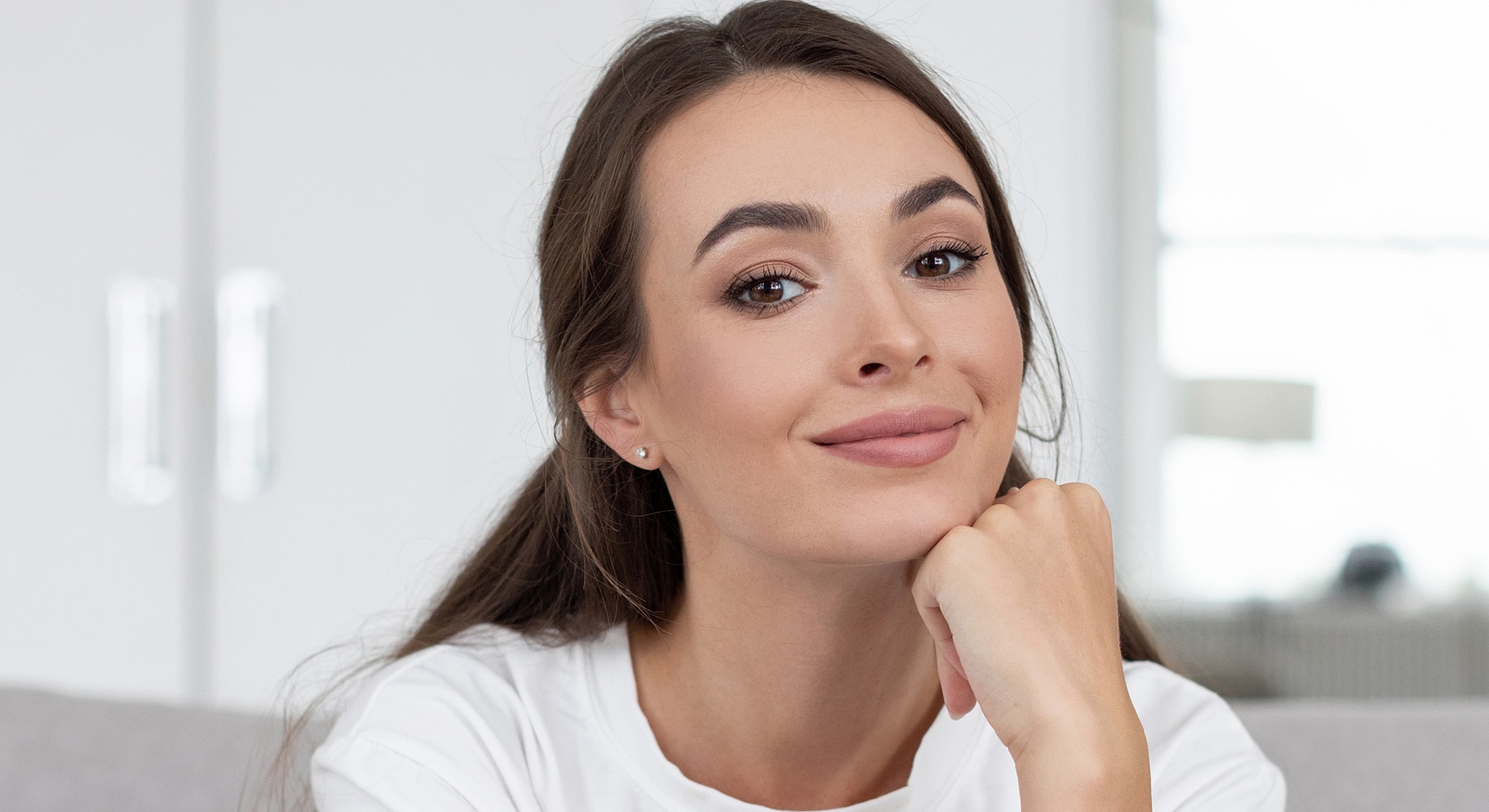 Smiling woman resting chin on hand.