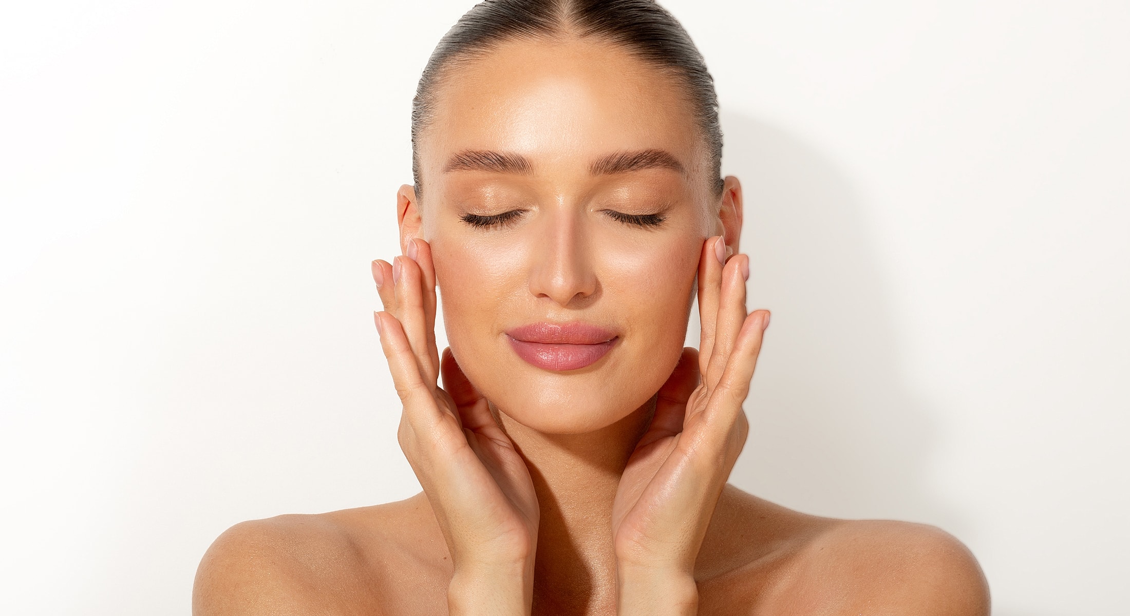 Woman gently touching her face, eyes closed.