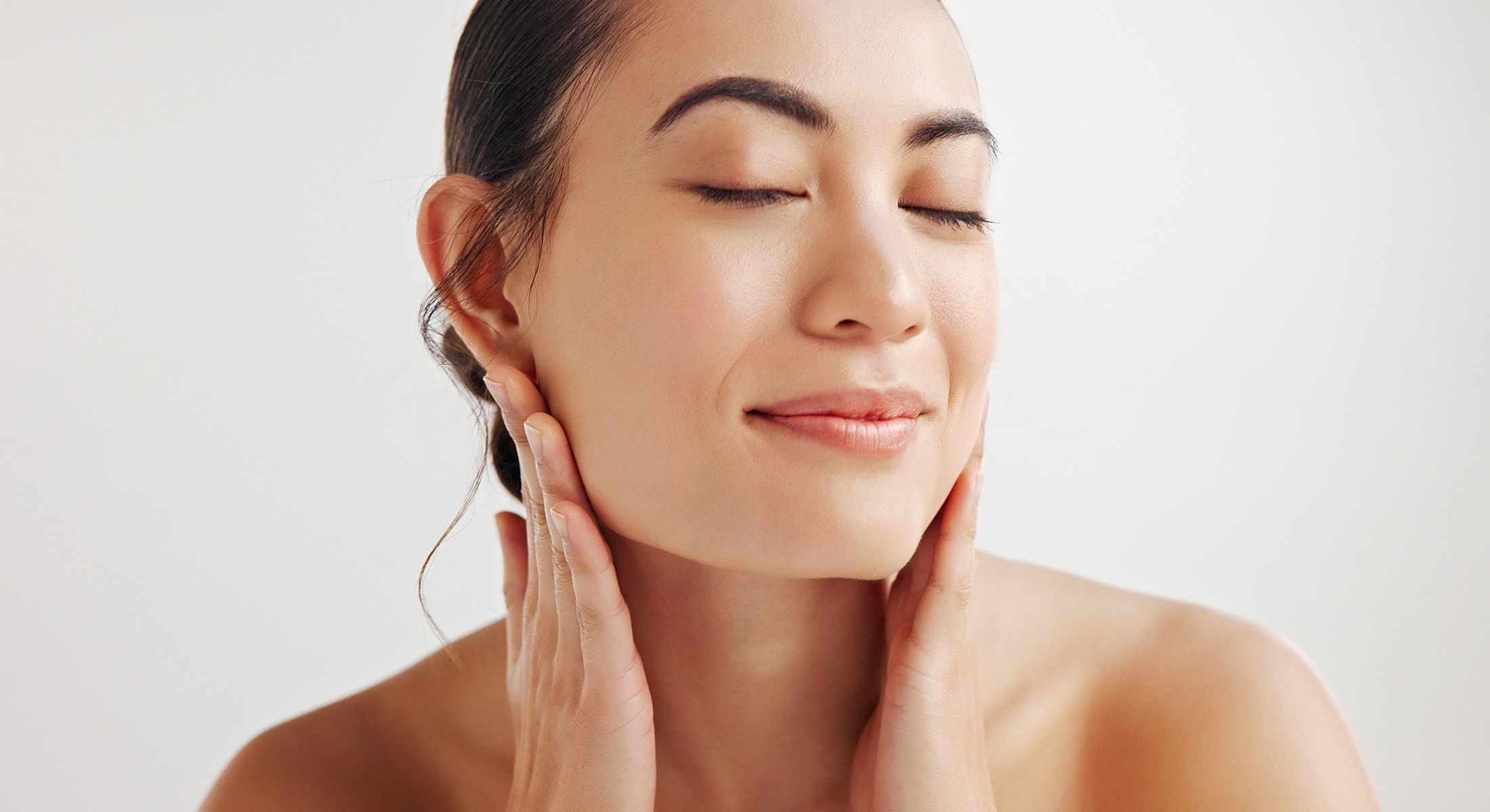 Woman gently touching her face with closed eyes.