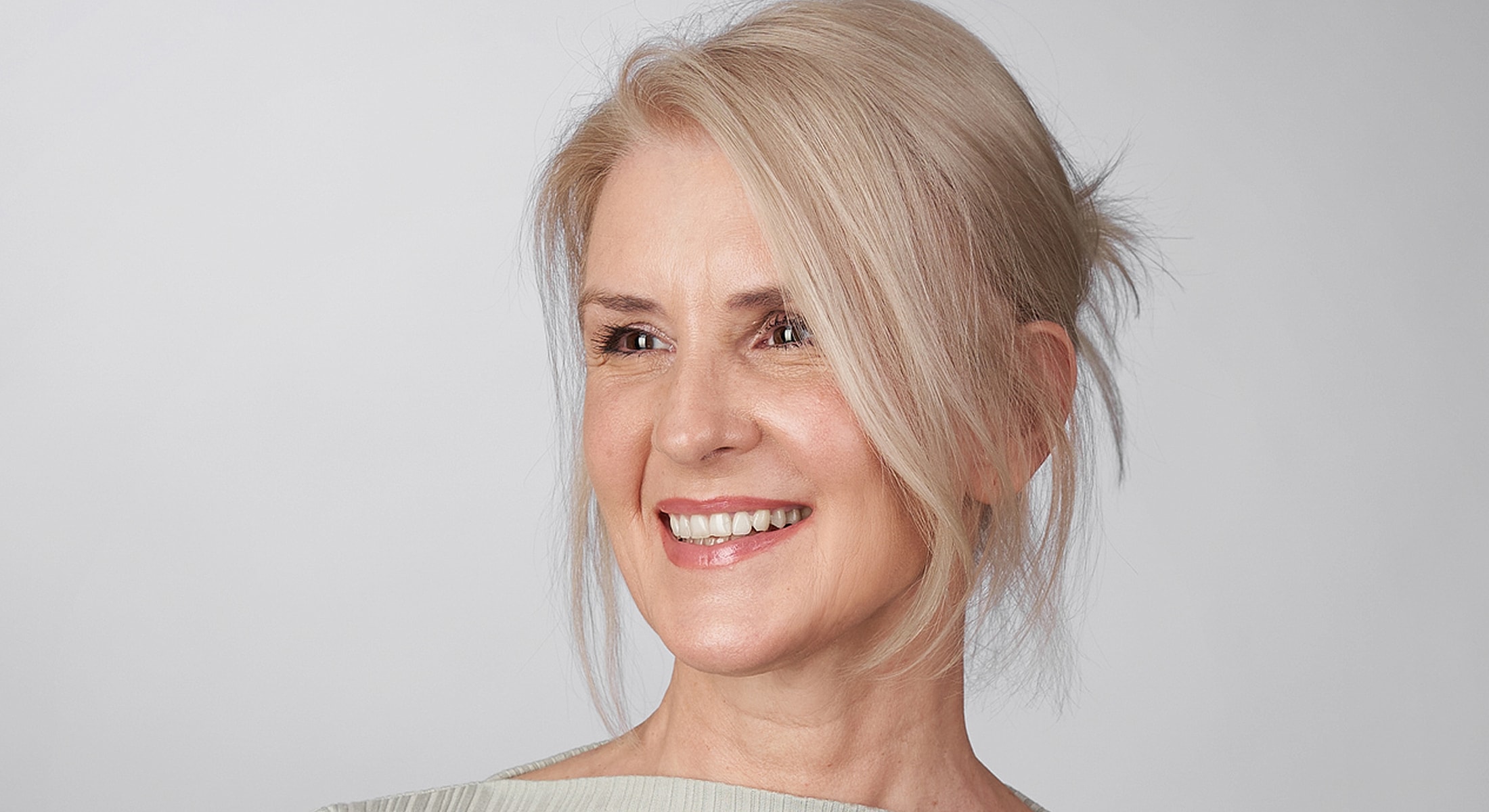 Smiling woman with blonde hair against neutral background.